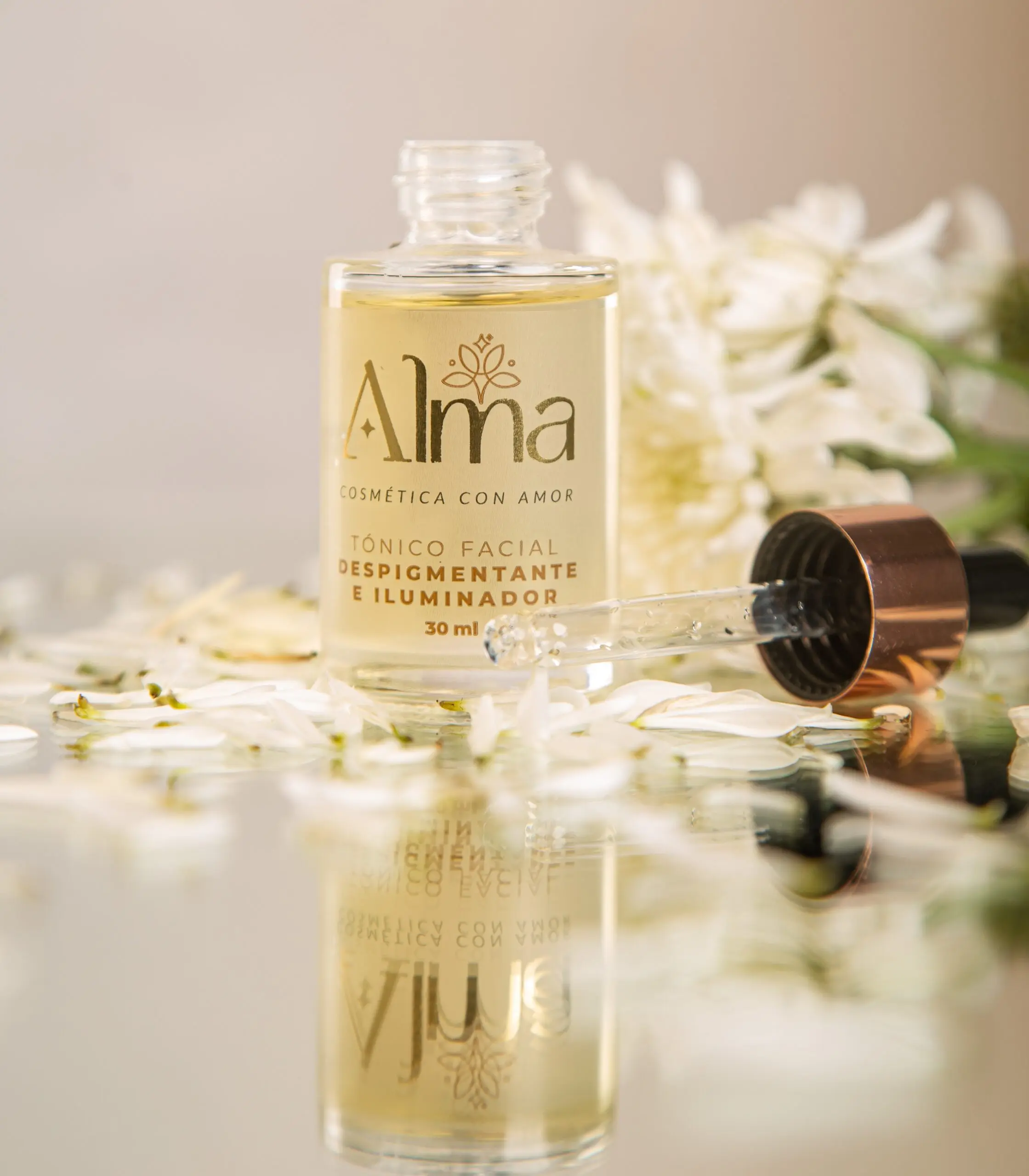 Tónico facial Alma despigmentante e iluminador en frasco de vidrio con gotero sobre pétalos.