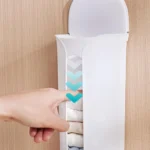 Estante de pared blanco para guardar ropa interior, con mano presionando para sacar una prenda.