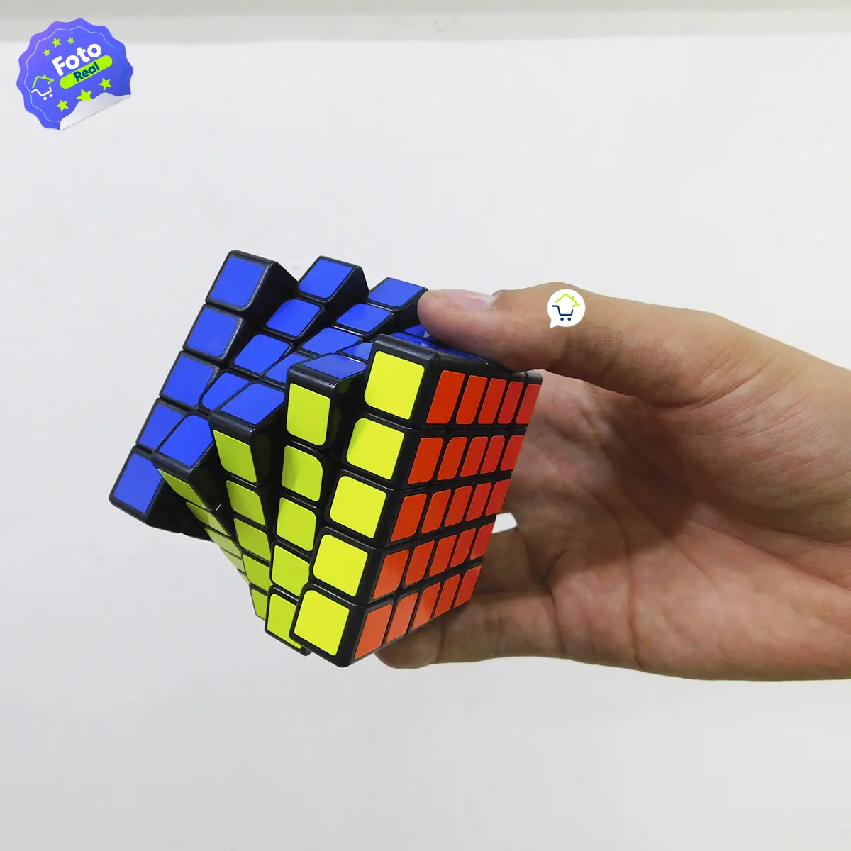 Cubo Rubik 5x5 en mano, rompecabezas mágico de colores azul, amarillo y rojo.