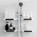 Estantes giratorios para baño con dispensadores y lociones sobre barra de ducha.