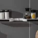Estante de almacenamiento giratorio para baño, con frascos de condimentos en pared gris.
