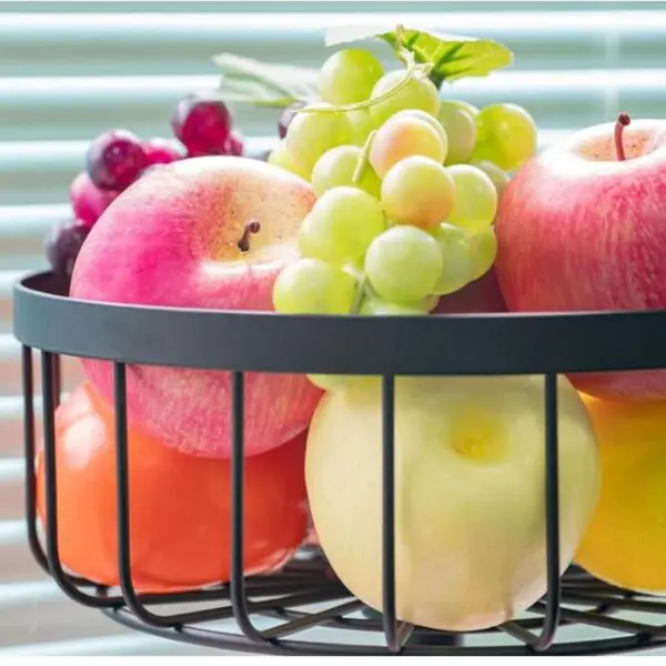 Estante organizador de 2 niveles con surtido de frutas frescas: uvas verdes, manzanas rojas y amarillas, y naranjas.