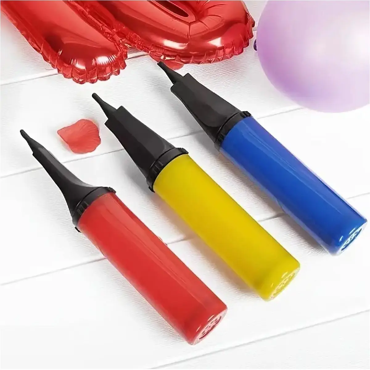 Infladores manuales para bolsas de aire, rojos, amarillos y azules, con globos y decoración festiva de fondo.