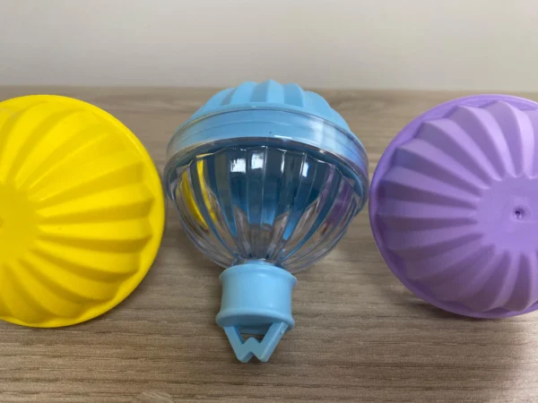 Set x4 moldes esféricos para hielo en silicona, uno amarillo, uno azul y uno morado, en mesa de madera.