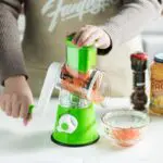 Rallador de verduras giratorio con base de succión picando zanahoria en un bol.