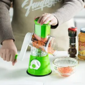 Rallador de verduras giratorio con base de succión picando zanahoria en un bol.