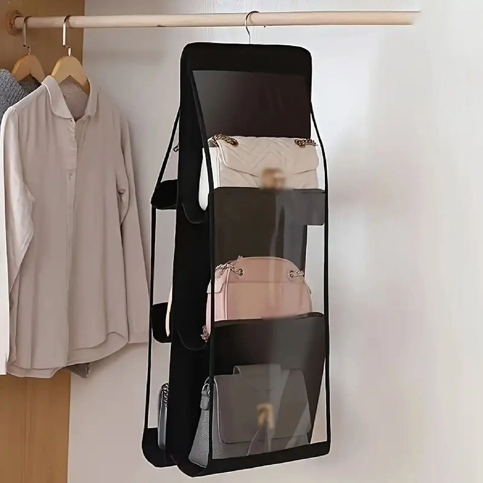 Organizador colgante negro para closet con 6 espacios para bolsos, uno blanco y uno rosa.