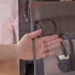 Mano revisando organizador de bolsos de 4 niveles en armario gris.