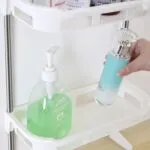 Organizador de baño de 3 niveles con jabón líquido verde y loción azul en estante blanco.
