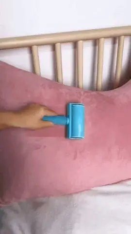 Rodillo quitapelusas azul sobre almohada rosa, ideal para hogar y mascotas.
