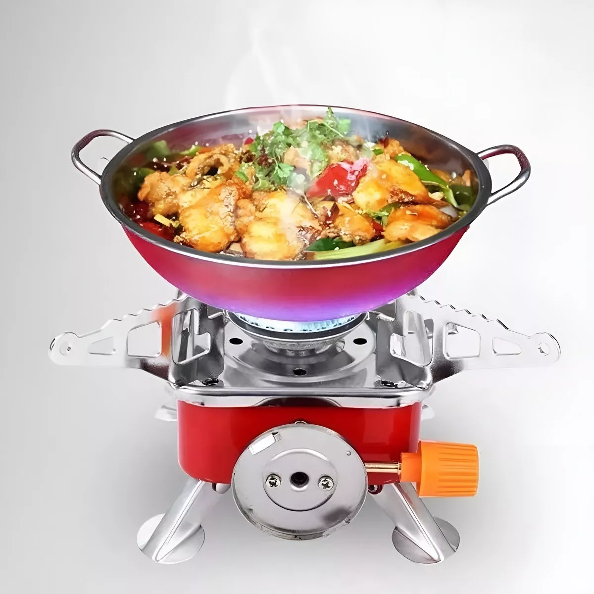 Estufa de gas portátil con sartén de comida humeante cocinándose sobre una llama azul.