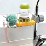 Soporte metálico para grifo con esponja, cepillo dispensador y pelador de cocina.