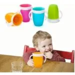 Niño sonriente con vaso entrenador 360° antiderrame en mesa de madera.