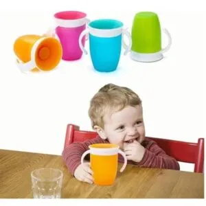 Niño sonriente con vaso entrenador 360° antiderrame en mesa de madera.