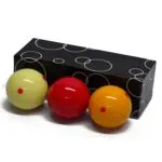Juego de 3 bolas de billar 3 bandas, colores amarillo, rojo y naranja, sobre superficie blanca.