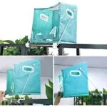 Cesta plegable Dady azul turquesa colgando en barandal con plantas verdes.