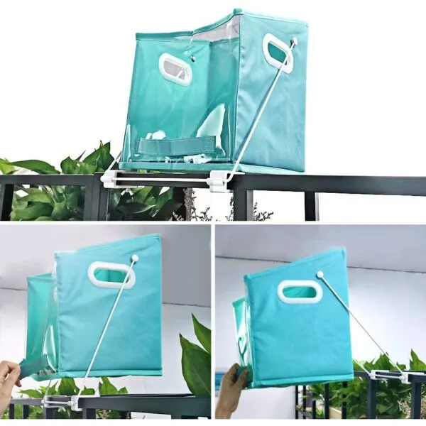 Cesta plegable Dady azul turquesa colgando en barandal con plantas verdes.