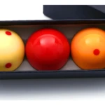 Tres bolas de billar de 3 bandas (amarilla, roja y naranja) en estuche negro, listas para jugar.