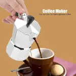 Cafetera italiana de aluminio veriendo café expreso en taza marrón con galleta.