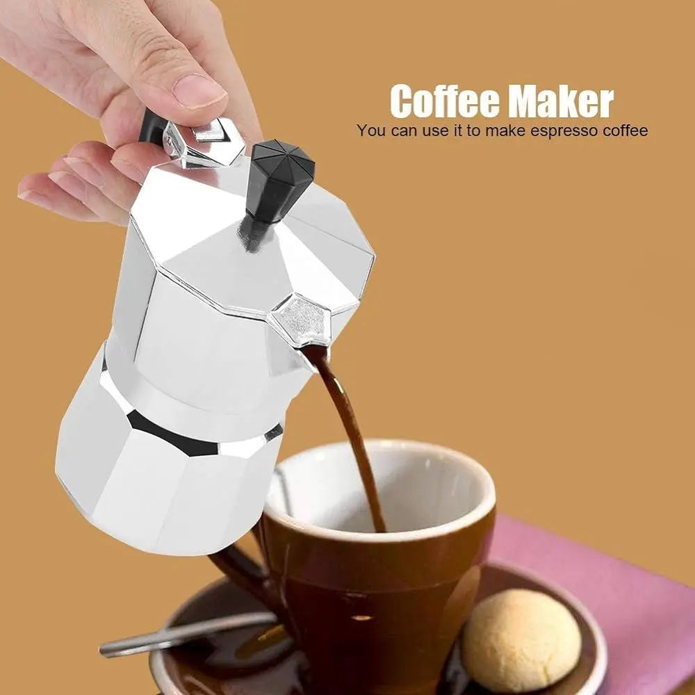 Cafetera italiana de aluminio veriendo café expreso en taza marrón con galleta.