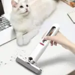 Mini trapeador para escritorio limpiando migas cerca de un gato blanco y azul en una mesa.