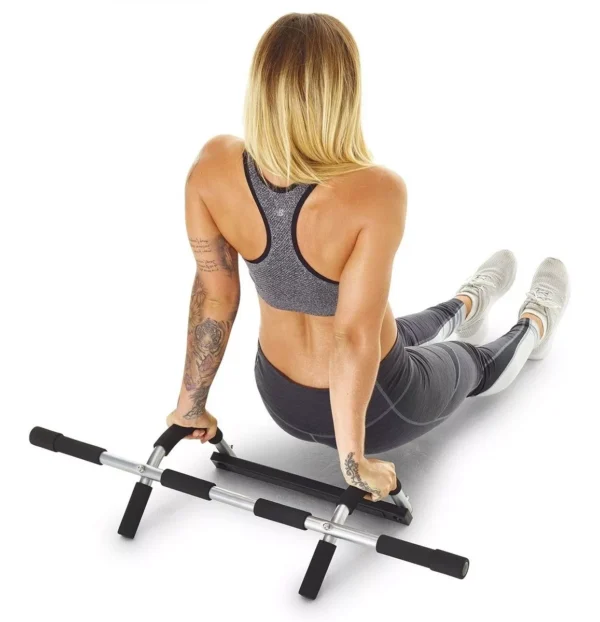 Mujer haciendo abdominales en barra para marco de puerta con piernas extendidas.