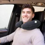 Hombre sonriente con almohada inflable para cuello viajera en auto.