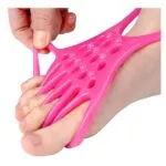 Banda elástica rosa para ejercitar y separar los dedos de los pies, vista cercana.