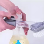 Set x2 cepillos para loza con dispensador de jabón, vertiendo agua.