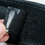 Corrector de postura con cierre de velcro plateado y material negro transpirable.
