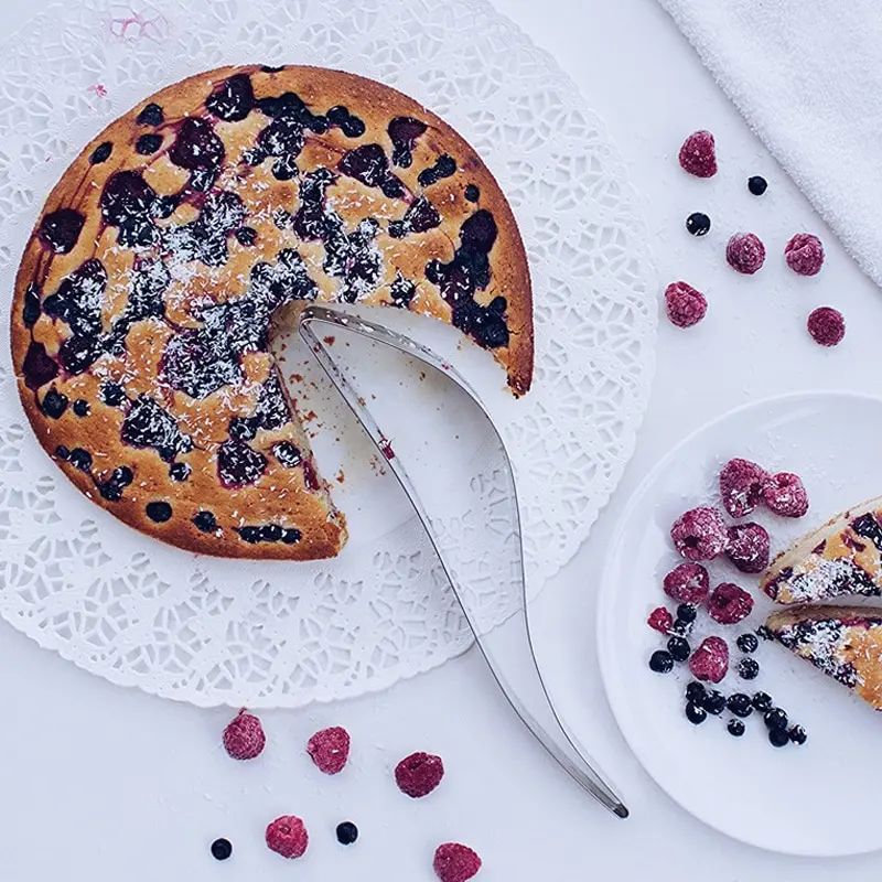 Porcionador de tortas con frutos rojos y bizcocho de arándanos espolvoreado con coco rallado.