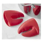 Guantes antiquemaduras de silicona roja con forma de pinza de langosta, usados en una olla.