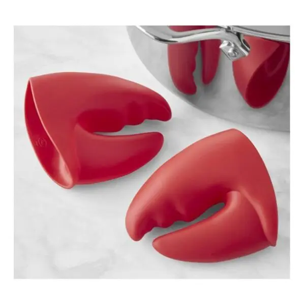 Guantes antiquemaduras de silicona roja con forma de pinza de langosta, usados en una olla.