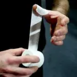 Manos aplican venda autoadhesiva para crossfit de rollo blanco.