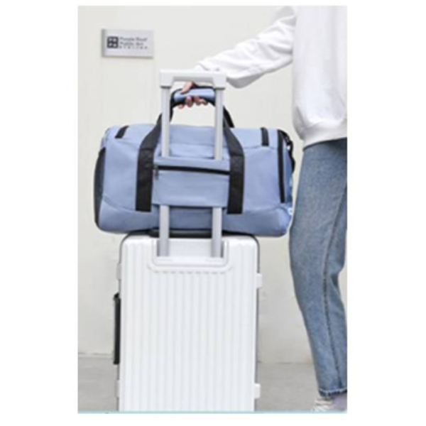 Bolso de viaje grande azul claro con compartimento frontal, apilado sobre maleta blanca con ruedas.