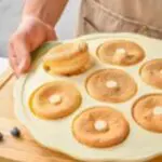 Molde de silicona para donas con varias unidades doradas y dos arándanos al lado.