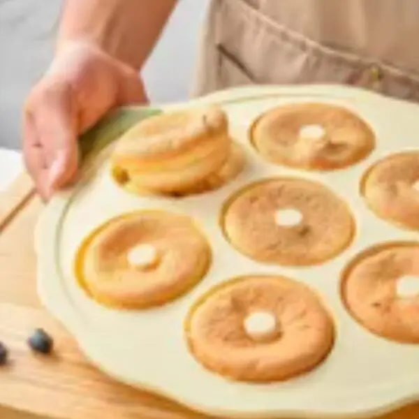 Molde de silicona para donas con varias unidades doradas y dos arándanos al lado.