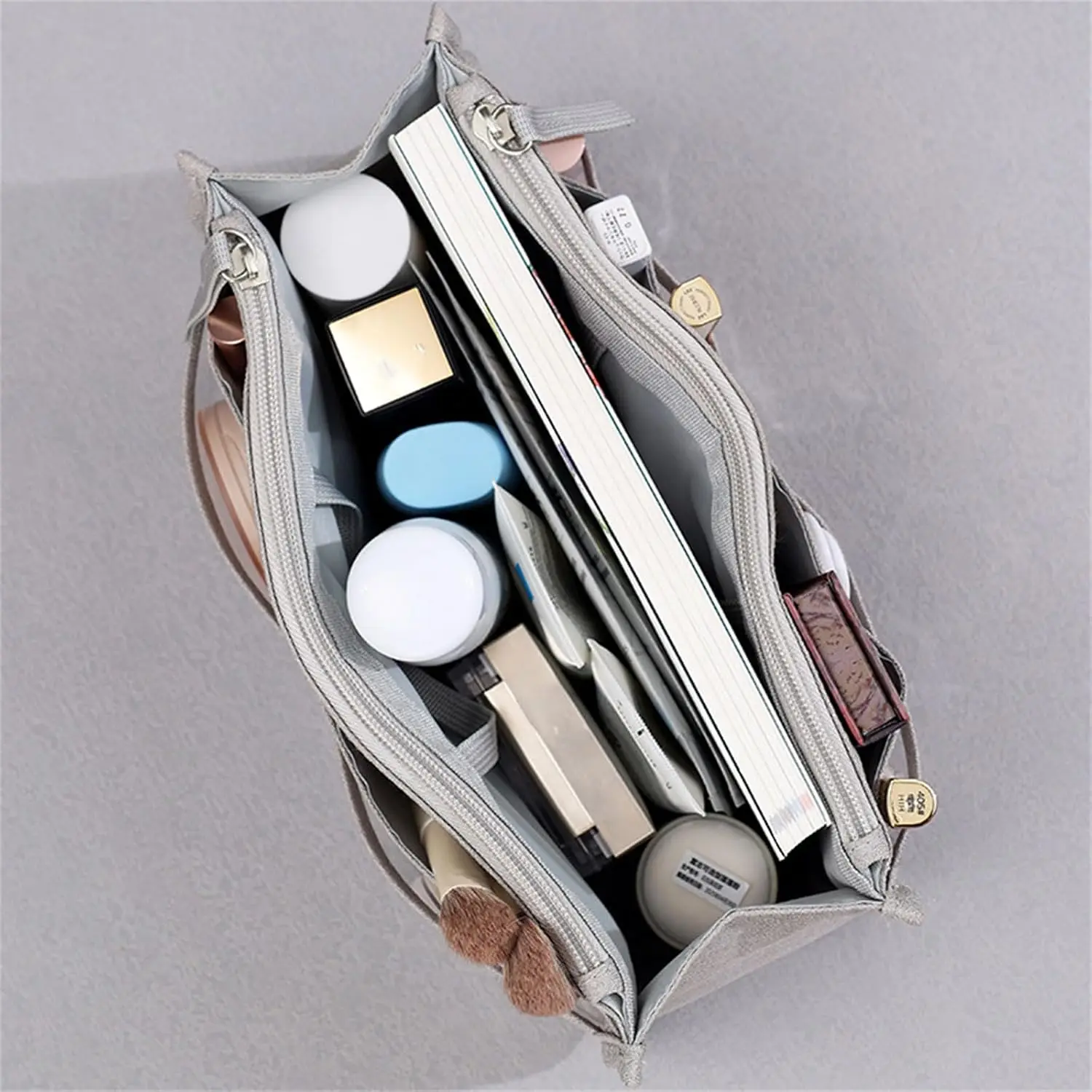Bolso organizador Oasis gris con libros y maquillaje, visto desde arriba.