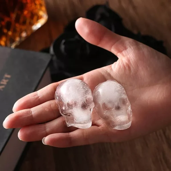 Molde calavera hielera Drop con dos cubitos de hielo en forma de calavera sostenidos en una mano.