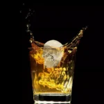 Molde calavera hielera con whisky espumoso y salpicaduras.