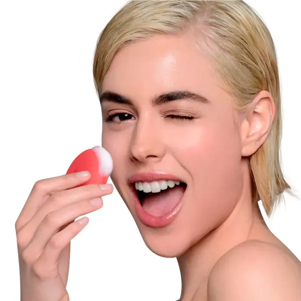 Mujer rubia con limpiador facial Foreo Luna Mini, masajeando su mejilla con espuma.
