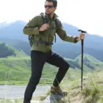 Bastón de trekking senderismo con linterna LED ajustable, hombre con mochila en montaña.