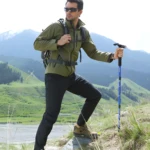Hombre con bastón de trekking senderismo linterna led ajustable en montaña.