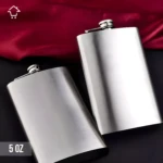 Licorera de acero inoxidable de 5 oz, diseño plateado, con tela roja y fondo negro.