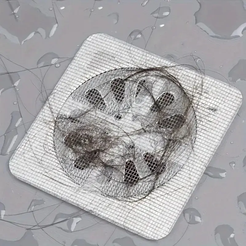 Set x100 mallas desechables para drenaje con pelo acumulado, tapando el desagüe en un baño.