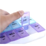 Pastillero semanal con compartimentos día y noche, tapa morada en mano.