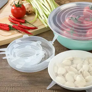 Set de 6 tapas de silicona flexibles cubriendo recipientes con tomates y ajo, junto a vegetales frescos.