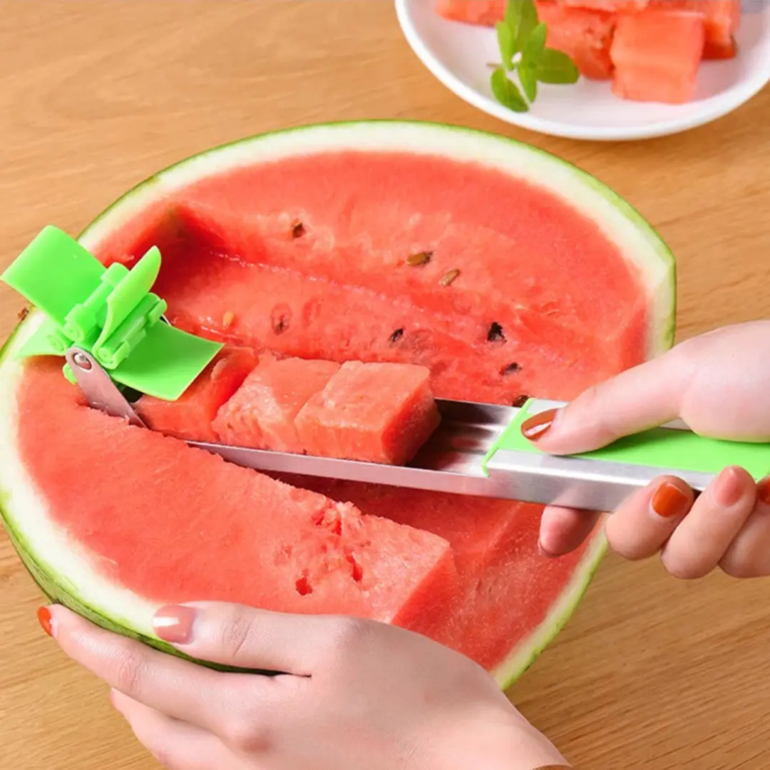 Cortador de frutas verde para cubos de sandía con mango metálico y accesorio giratorio.