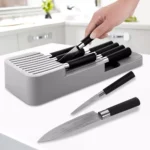 Organizador de cuchillos moderno gris con asas negras, cuchillos de acero damasco en primer plano y en bloque.