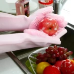 Guante Mágico Mg rosa para lavar frutas con cerdas de silicona en el lavaplatos.